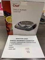 Box showing brand 'Master Chef' and product image of a black single burner cooktop with spiral heating element and control knob, along with a paper listing product specs.