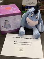 Photo showing Eeyore plush seated next to the themed box and sign describing the item.