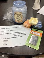 Photo of blue glass Scentsy warmer with wire caging and decal, alongside three wax melt bars and a fragrance carrier travel tin on a table with seller description sheet.