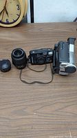 Overall view of cameras and lenses on table including Sony camcorder, Fujifilm point-and-shoot camera, and lenses.