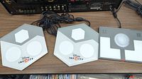 Two Disney Infinity game bases and one LEGO Dimensions base shown from top view on wood surface, branded logos visible.
