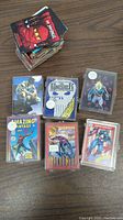 Pile of various Marvel and other non-sports trading cards on wood surface, including some in plastic holders showing characters The Punisher, Captain America, and Spider-Man.