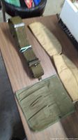 Photo of green ammunition belt and two padded canvas sleeves or shoulder protectors