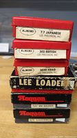 Stack of red and black Lee Precision and Teague branded boxes showing caliber labels for reloading dies and kits.