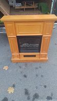 Front view of wooden electric fireplace with glass panel and vent below.