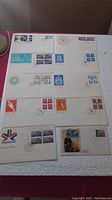 Image shows a group of Canadian first day issue stamp covers arranged on a white surface, each with various stamps and cancellation marks.
