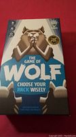 Front of unopened The Game of Wolf board game box showing wolf mascot and game title