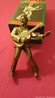 Elvis Presley Christmas ornament figure in bronze tone shown standing playing guitar with original green and red Hallmark Keepsake ornament box in background