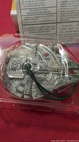 Close-up of the Millennium Falcon ornament with wiring inside plastic packaging.