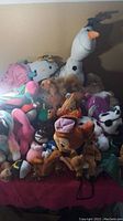 View of the full assortment of stuffed animals including Olaf snowman and various plush characters piled on a red surface.