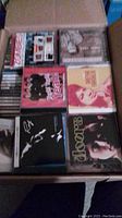 Top view of a box containing CDs, showing covers from The Doors, The Zombies, and a tribute to The Beatles among others.