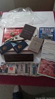 Overview of lot contents showing military books, photographs, wooden nameplate, and other paper memorabilia.