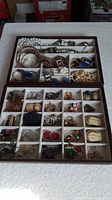 Two open jewelry boxes showing assorted vintage jewelry items arranged in small compartments