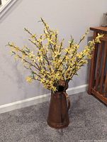 Copper pitcher with artificial yellow flower branches placed inside, showing height and general condition.