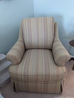 Front view of Basset upholstered swivel chair showing striped fabric upholstery, cushioned seat and back with rolled arms and skirt at base.
