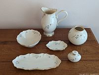 Overview of pitcher, small vase, small dish, perfume bottle, ring holder, and tray showing floral design and gold trim