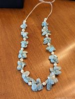 Full view of the light blue aquamarine chip and white freshwater pearl necklace laid flat on wood surface