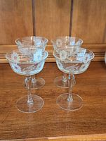Four crystal champagne or sherbet glasses arranged in a group showing the floral etching.