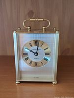 Front view of the Hamilton mantle clock showing the gold-tone case, Roman numeral dial, and clock hands.