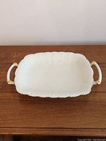 Full view of rectangular white Lenox platter with two handles and gold trim on a wooden surface