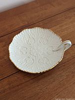 Top view of white ceramic nappy dish with embossed floral pattern and gold rim