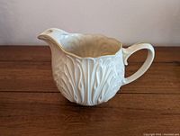Side view of Lenox Cottage Collection porcelain pitcher showing acanthus leaf design and gold-trimmed ice lip and handle.