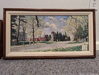 Framed print of a springtime scene in Stockbridge with cyclists and buildings, wood frame with white linen mat, 31"x11".