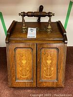 Front view of antique wooden coal scuttle with wood inlay and brass handle
