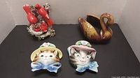 Overview showing all items in the lot including cardinals group, two cat face wall mounts and swan figurine.