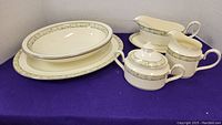 Full set view on purple cloth background showing platter, casseroles, gravy, milk, and sugar bowl.