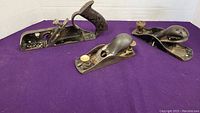 Front angle view of three metal planes on purple background
