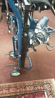 Side view showing folded portable compound miter saw on a wheeled stand, capturing the full assembled unit in resting position.
