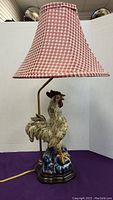 Full view of the lamp showing ceramic rooster base and red gingham shade.