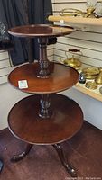 Full view of entire three-tier round wooden accent table showing its structure and tier sizes.