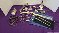 Full lot showing various silverplated serving spoons, forks, napkin rings, salt and pepper shakers, match holder and bone-handled cutting utensils in pouch