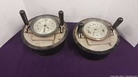 Two vintage Calculagraph time recorders positioned side by side showing levers and dials.