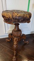 Front view showing round leather seat and carved wood base