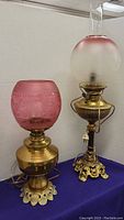 Both vintage pink glass and brass table lamps together with visible details of glass shades and brass bases.