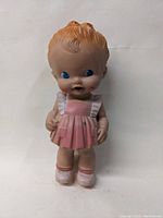Front view of 1950s vintage rubber doll with pink dress and molded hair.