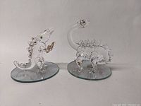 Two clear glass dinosaur figurines from a front angle on white background