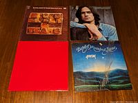 Four vinyl album covers placed on a wooden surface: Blood Sweat and Tears Greatest Hits, James Taylor Sweet Baby James, Bright Morning Star Arisin', and Billy Joel Double Live Concert with Russian Cyrillic lettering.
