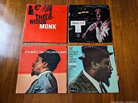 Four Thelonious Monk vinyl LP album covers on wooden surface, featuring Volume Two The Genius of Modern Music and others.