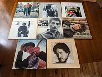 Eight Bob Dylan vinyl albums with covers laid out on table showing arrangement and condition.