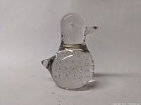 Front and side view of the transparent glass penguin figurine showing air bubbles within the body and smoothly sculpted form.