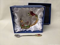 Glass mug with butterfly and rose enamel metal handle and base mount along with a matching spoon in fitted satin-lined box.