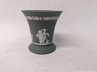 Front view of green jasperware Wedgwood vase with white cherub and garland decoration