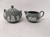 Front and side view of the sugar bowl with lid and creamer showing green jasperware with white classical reliefs.