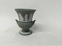 Green Wedgwood Jasper Ware urn-shaped footed vase with white classical relief figures and motifs, shown from front angle.