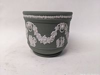 Front side view of green Wedgwood jasperware bowl with classical white relief decoration including garlands and figures.
