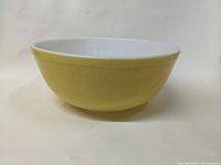 Front and side view of the yellow Pyrex mixing bowl showing the smooth yellow exterior and white interior.